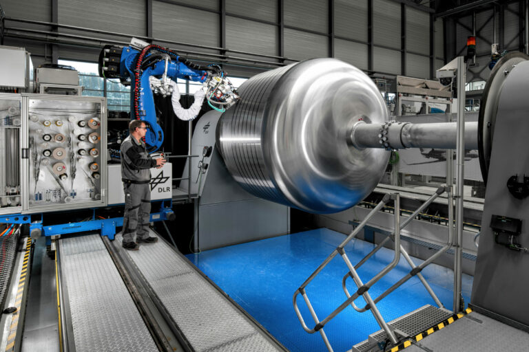 Zeigt dir GroFi-Anlage mit einem Roboterarm in betrieb. Dieser legt Tape auf dem Werkzeug für die Tankherstellung ab.